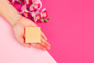 female  manicure. Beautiful young woman's hands holding a soap on pastel pink background - Image