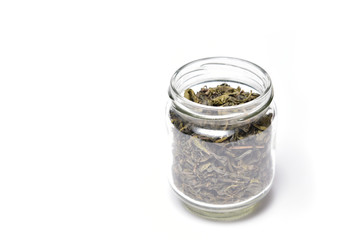 Dried leaf of tea in jar on white background