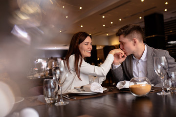 beautiful caucasian couple have dinner in rich restaurant, they happy together, on a date. man and woman in love, look at each other, man kiss hand of woman