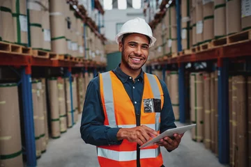 Fotobehang Happy male factory manager using digital tablet in warehouse while standing against goods shelf looking at camera © StratfordProductions