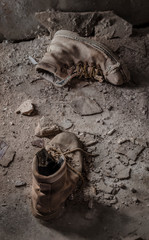 Botas de cuero viejas abandonadas en medio de la suciedad.