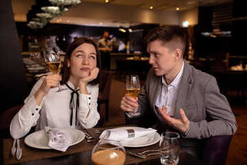 bad evening in a restaurant. young caucasian couple quarreled in representative luxury restaurant, they don't talk with each other. woman tired of endless quarrels