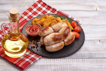 Grilled sausages, bratwurst with tomato sauce, spices and herbs on a stone plate, rustic background