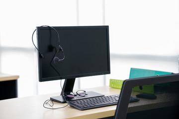 High angle view of headphones on blank computer monitor at wooden table