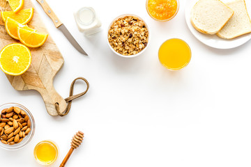 Morning granola near toast and oranges on white background top-down frame copy space