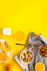Morning granola near toast and oranges on yellow background top-down frame copy space