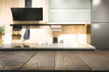 Empty wooden tabletop and defocused modern kitchen for design and display your products. Abstract background.