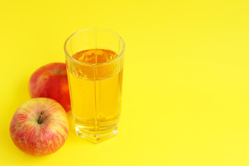 Apple juice and red apple on a yellow background