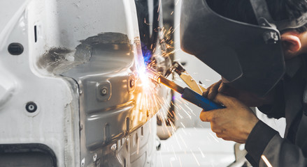 Worker welds car. Metalworking with carbon dioxide welding.