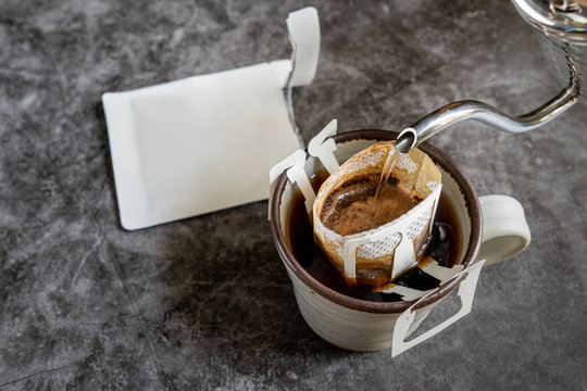 Pouring water on coffee grind ,coffee drip bag and pottery mug on stone table background