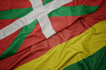waving colorful flag of bolivia and national flag of basque country.