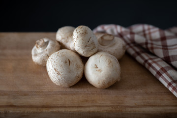 several fresh champignons laying on wooden cutting board