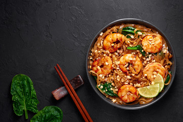 Prawn Pad See Ew in black bowl at dark slate background. Pad See Ew is thai cuisine dish with rice noodles, prawns, soy and oyster sauces and greens. Thailand food. Copy space. Top view