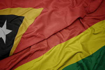 waving colorful flag of bolivia and national flag of east timor.