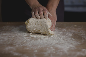 woman kneading bread dough on wooden table