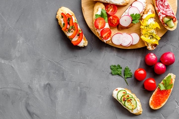 Set of bruschetta on cutting board on grey background top-down copy space