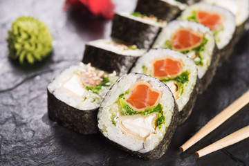 Closeup of sushi roll with salmon on a black slate background. japanese food menu