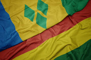 waving colorful flag of bolivia and national flag of saint vincent and the grenadines.
