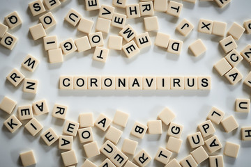 Coronavirus spelt on scrabble tiles surrounded by other tiles in the centre