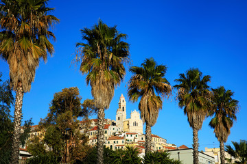 Fototapeta premium Cervo (IM), Italy - December 30, 2017: Cervo village view trough palms trees, Italian Riviera, Imperia, Liguria, Italy