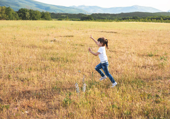 Active girl runs on the field in happy vacation. Kid love the freedom of the nature