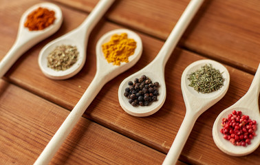 food, culinary and unhealthy eating concept - spoons with different spices on wooden table