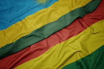 waving colorful flag of bolivia and national flag of rwanda.