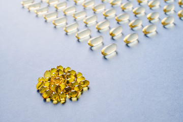 Yellow capsules with vitamin D on a blue background. Sunshine vitamin.
