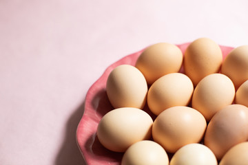 Plate with chicken eggs on pink background