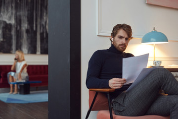Portrait of handsome bearded man holding documents while sitting in elegant cafe interior with...