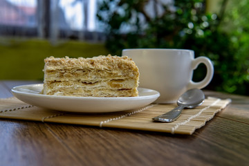 Cup of tea with cake on brown table background
