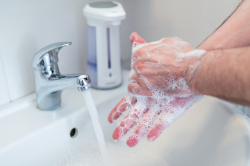 Hygiene concept. Washing hands with soap under the faucet with water, washing hands with soap over...