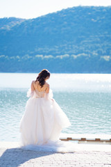 Fototapeta na wymiar rear view of bride in white dress on lake
