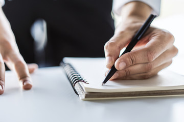 Man writes with a pen in diary in a sunny office, business and education concept. Close up
