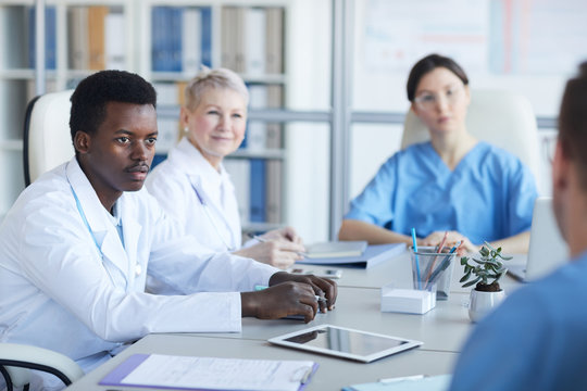 Portrait Of Young African-American Doctor Listening To Colleague Committee During Medical Conference, Copy Space