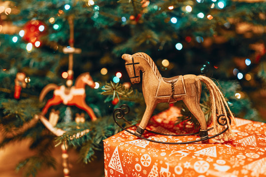 Christmas hobbyhorse made of wood on a present near a Christmas tree