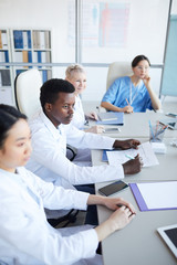 High angle view at young African-American doctor sitting at table during medical conference with...