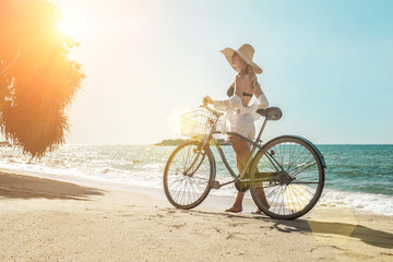 Fototapeta premium Happiness woman traveler with her bicycle rides on sea coastline