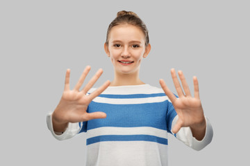 gesture, finger counting and people concept - smiling teenage girl showing hands or ten fingers over grey background