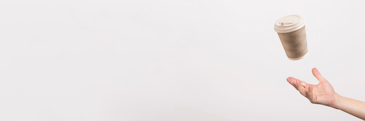 Obraz premium hand catches a cardboard glass on a light cardboard background. Concept of coffee, tea, advertising, coffee breaks. Banner