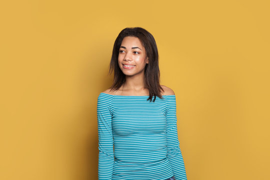 Black Woman Smiling. Girl In Striped Blue Shirt On Yellow Background