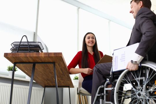 Portrait of cheerful smiling company manager interviewing candidate on vacancy. Disabled man sitting in wheelchair. Adaptation of people with disabilities in society concept
