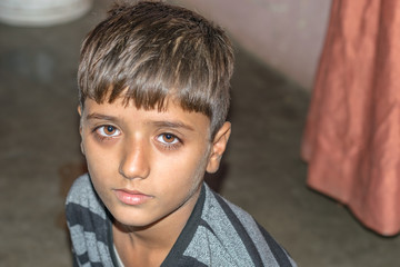 closeup of a poor staring hungry orphan boy in a refugee camp with sad expression and his eyes are full of pain