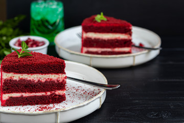 Cake Red velvet on two white plates, two servings. On a black background. Birthday, holidays, sweets.