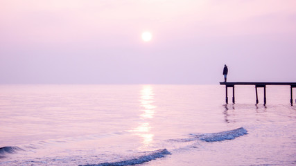 Fototapeta premium Girl standing on a pier in sunset
