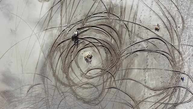 Dirt Bike rider preforming Donuts on a sandy beach in Bali, Indonesia, Top down aerial view.