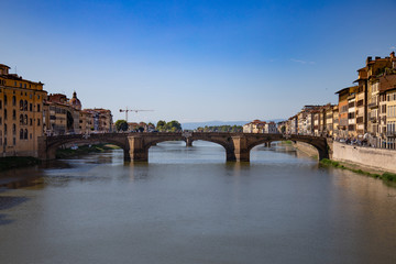 Fototapeta premium FLORENCE, ITALY - September, 2019: Italian traditional houses and architecture over Arno river with blue sky in Florence, Italy.