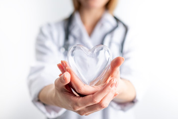 Female cardiologist doctor holding heart symbol on hands