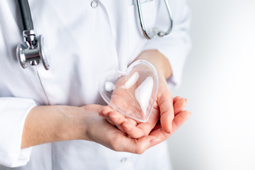 Female cardiologist doctor holding heart symbol on hands