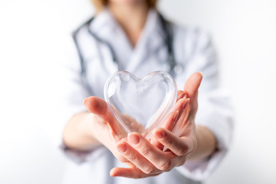Female cardiologist doctor holding heart symbol on hands